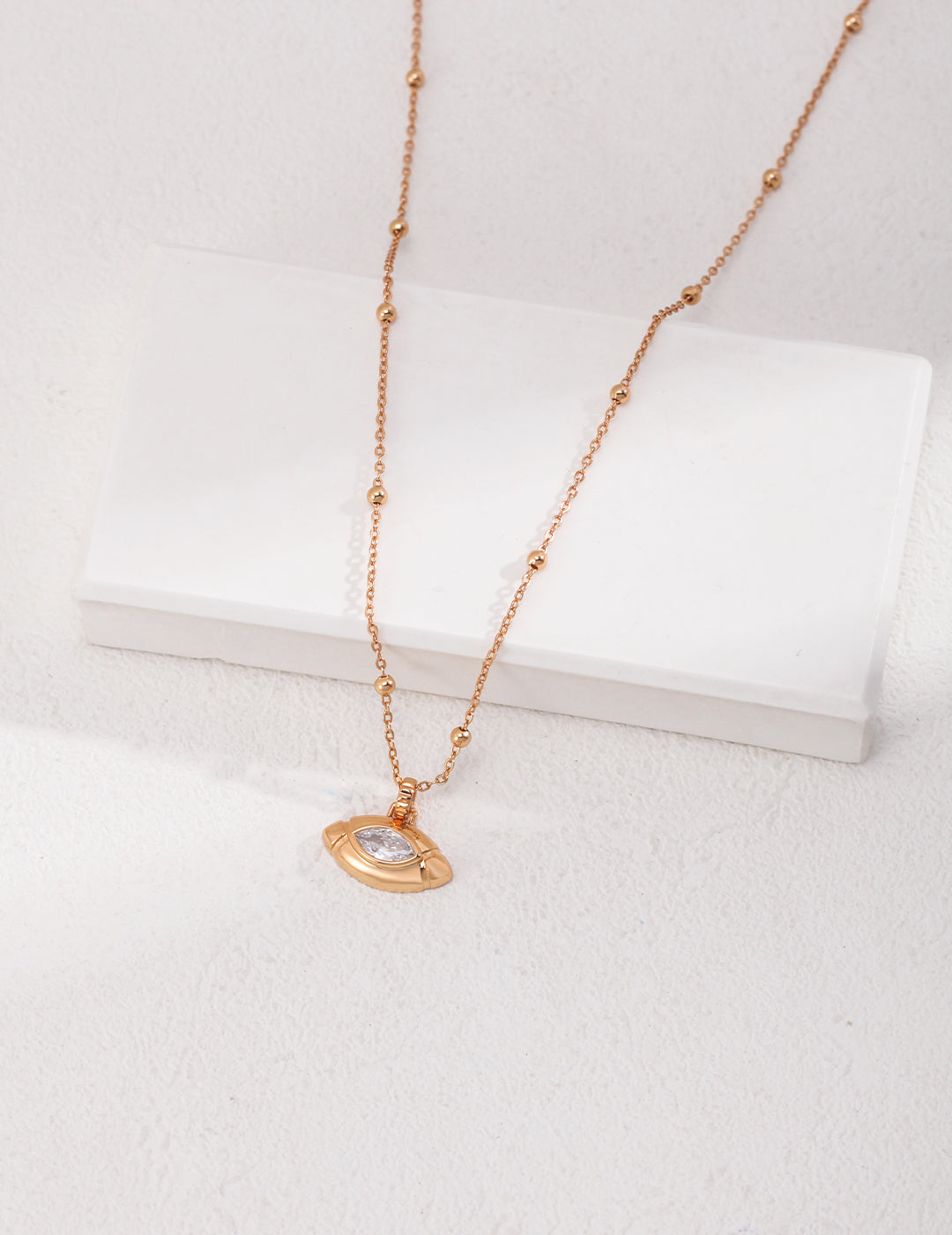 Gold plated necklace with small gold disc and cubic zirconia olive shape pendant.