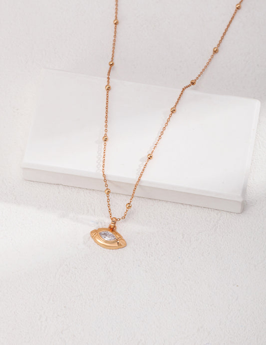 Gold plated necklace with small gold disc and cubic zirconia olive shape pendant.