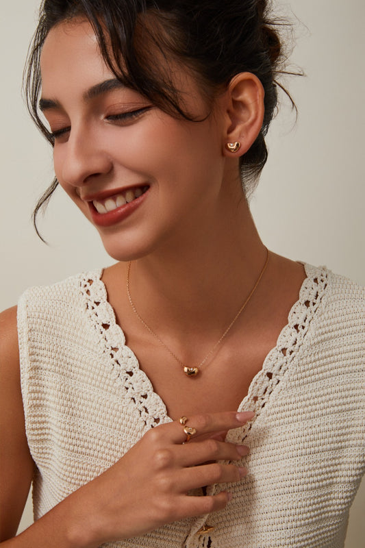 Close up shot of model who is smiling, wearing round bean shaped jewelry set, gold tone, aesthetic and elegant.