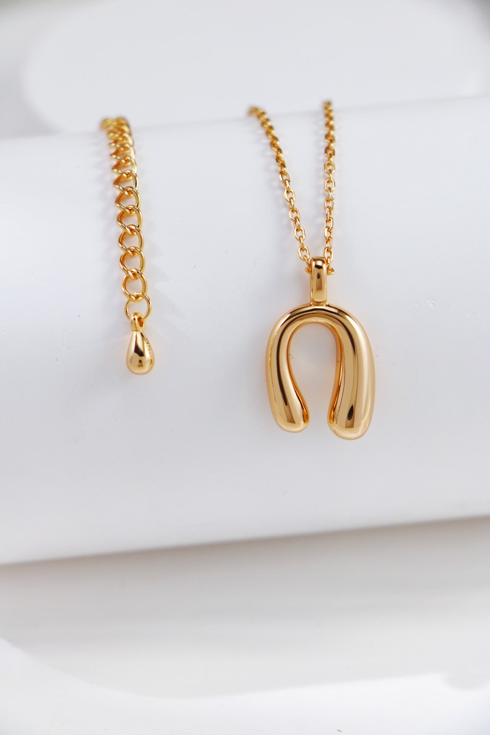 A gold necklace featuring a delicate horseshoe charm pendant, symbolizing luck and elegance.