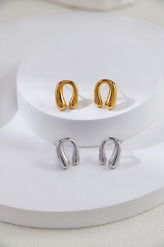 Two elegant horseshoe earrings in gold and silver displayed against a clean white background.