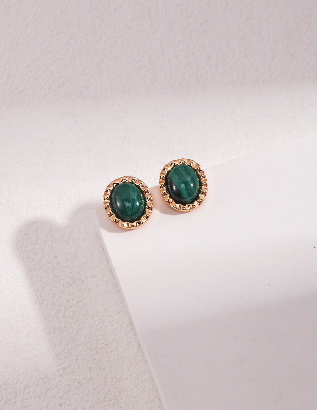 Elegant gold malachite stud earrings displayed on a white surface, adding a pop of color.