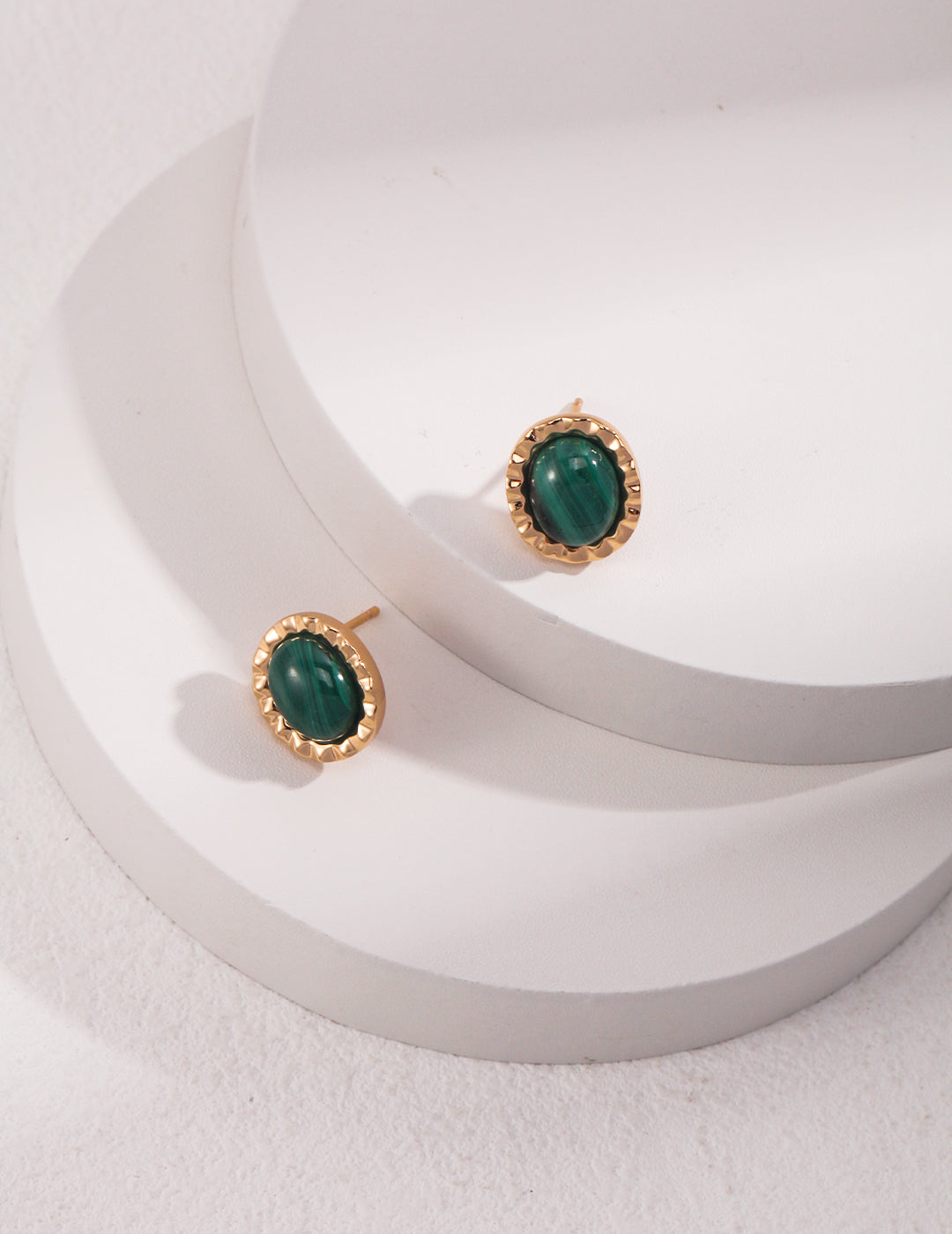 Gold malachite stud earrings on a white surface.