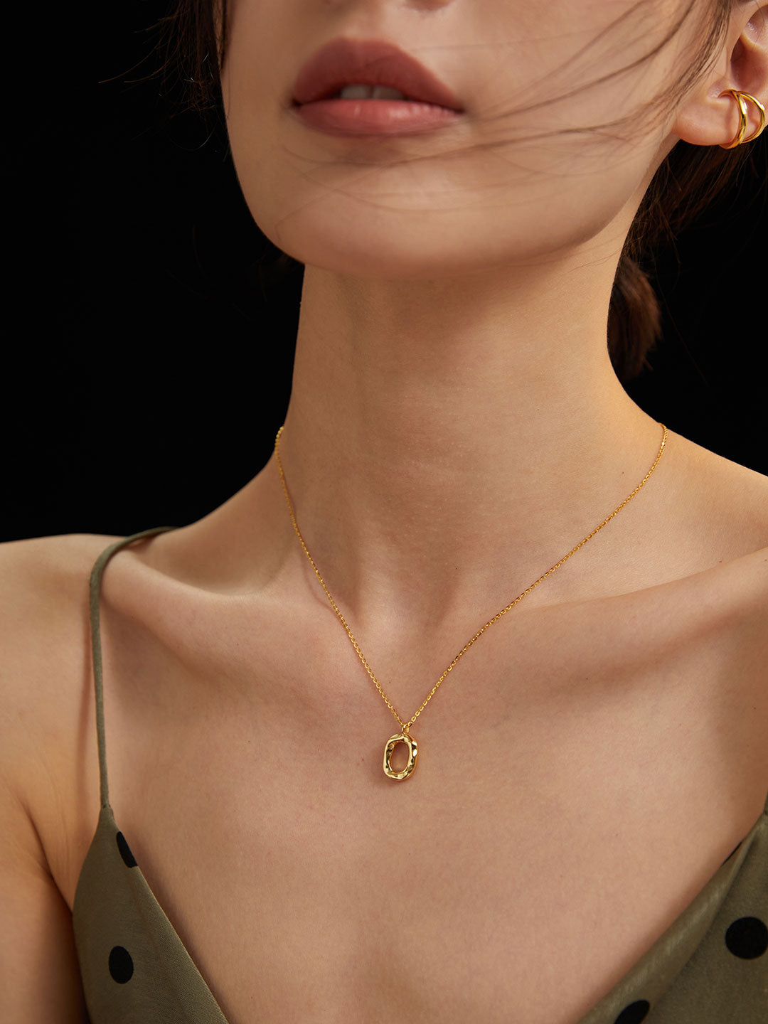 A stylish woman wearing a sleek gold necklace and earrings, radiating confidence and elegance.