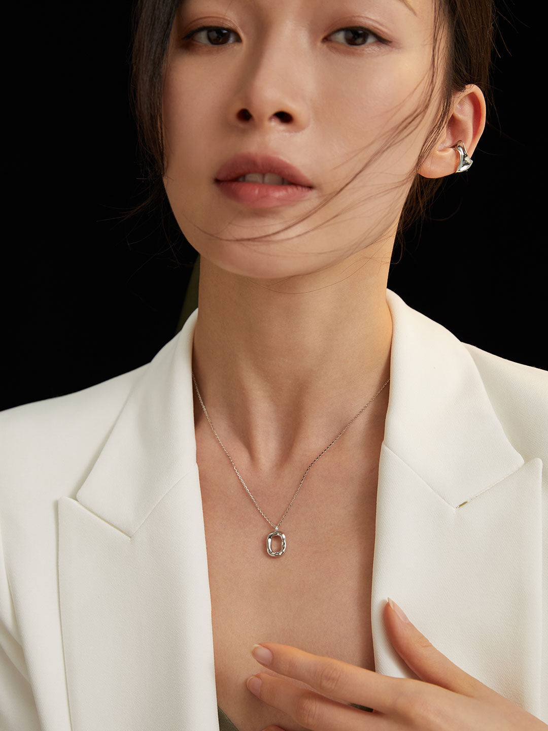 A confident model wearing a tailored white blazer and a statement necklace, embodying sleek elegance.