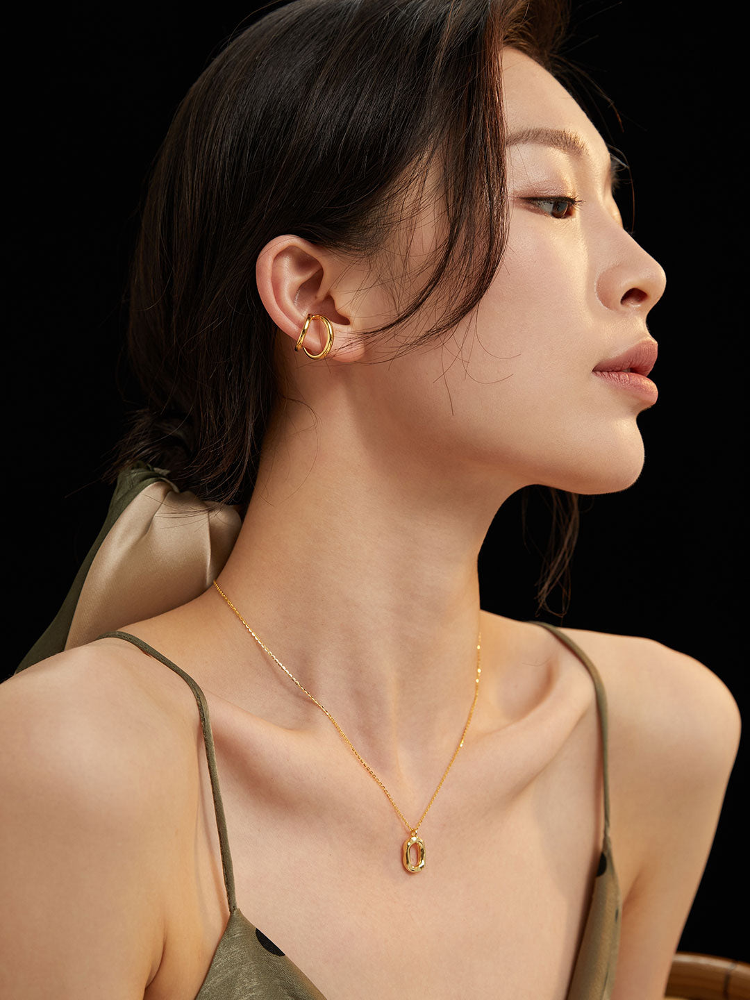 A woman models a sleek gold necklace and earrings, highlighting her sophisticated style and elegance.