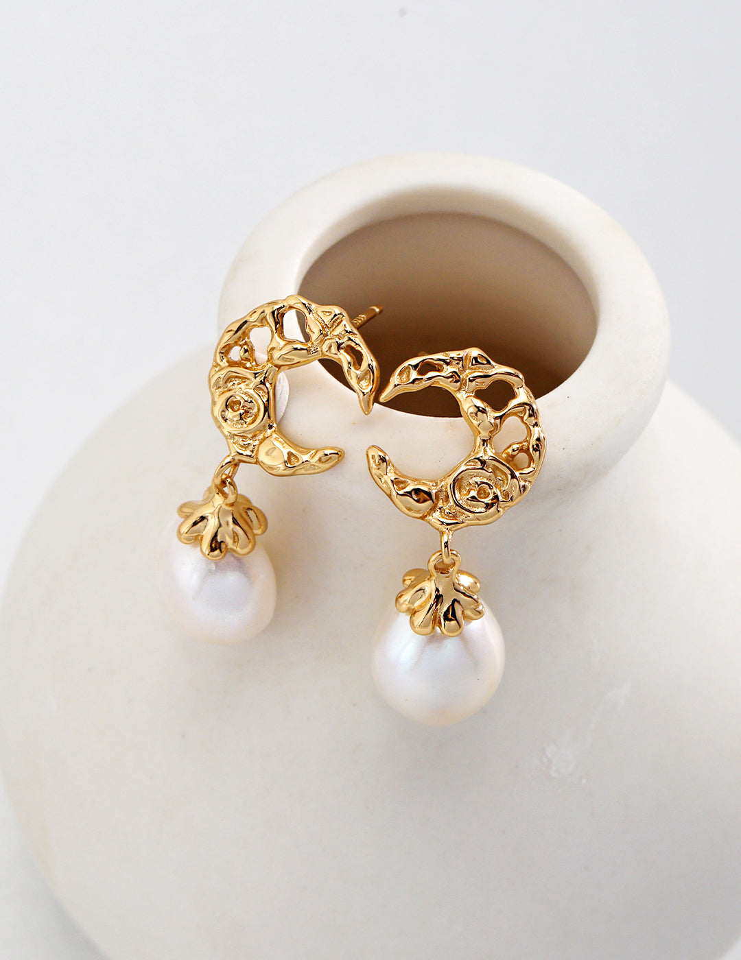 Stylish gold earrings with pearl dangles, designed in the shape of a crescent moon.