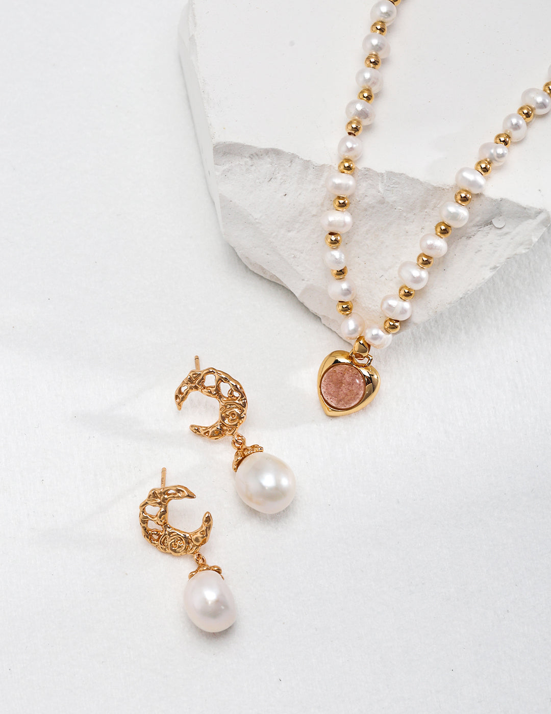 A stunning gold necklace and earrings set with freshwater pearl dangles, featuring a crescent moon design.