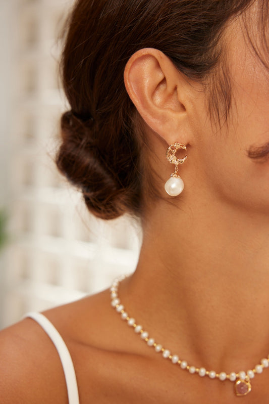 A woman in a pearl necklace and pearl earrings, highlighting her refined and classy appearance.