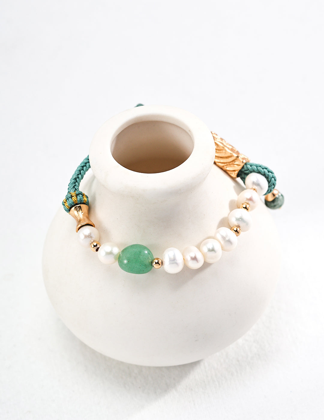 White vase with stunning turquoise bracelet showcasing jasper and pearls.