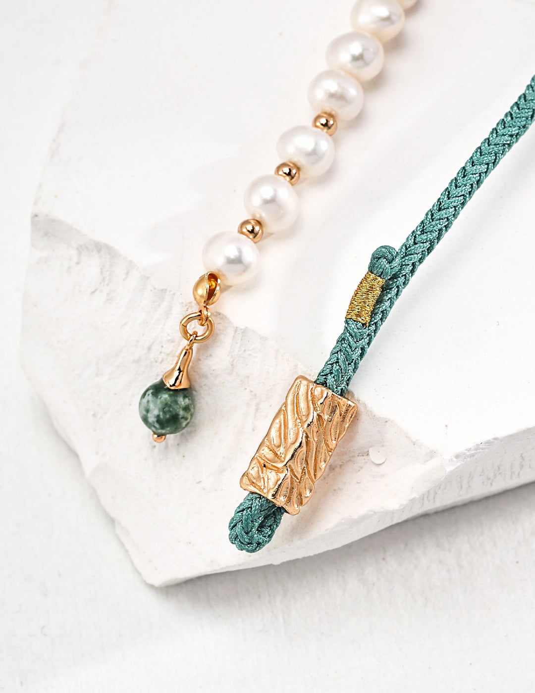 Close-up shot of green turquoise bracelet with gold clasp and pearl accents.