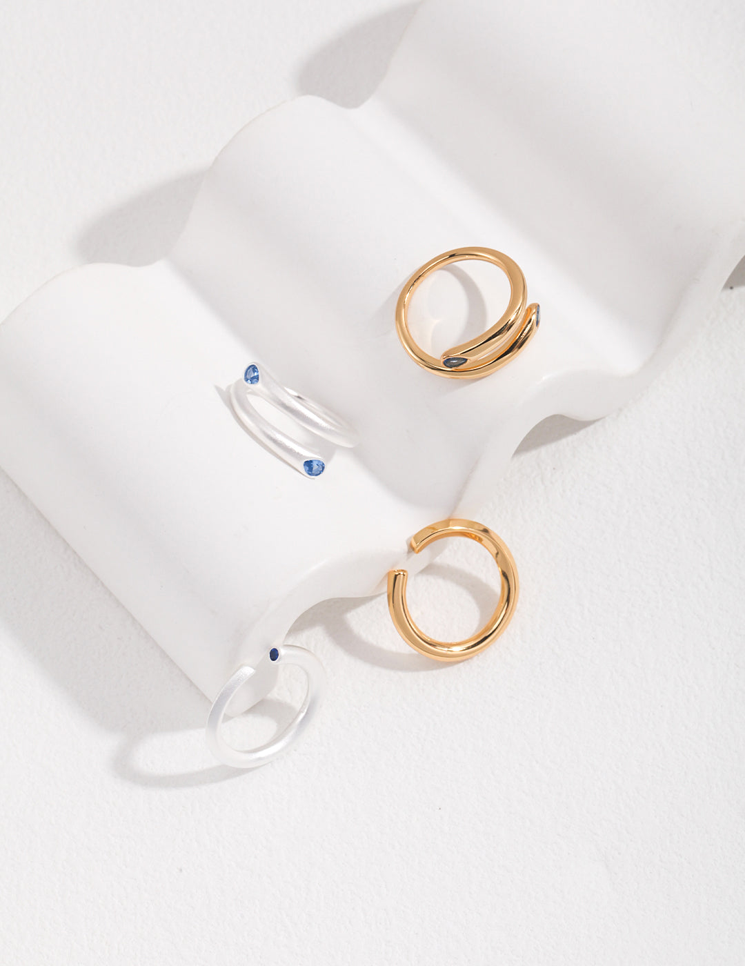 Four minimalist gold rings with aquamarine stones.