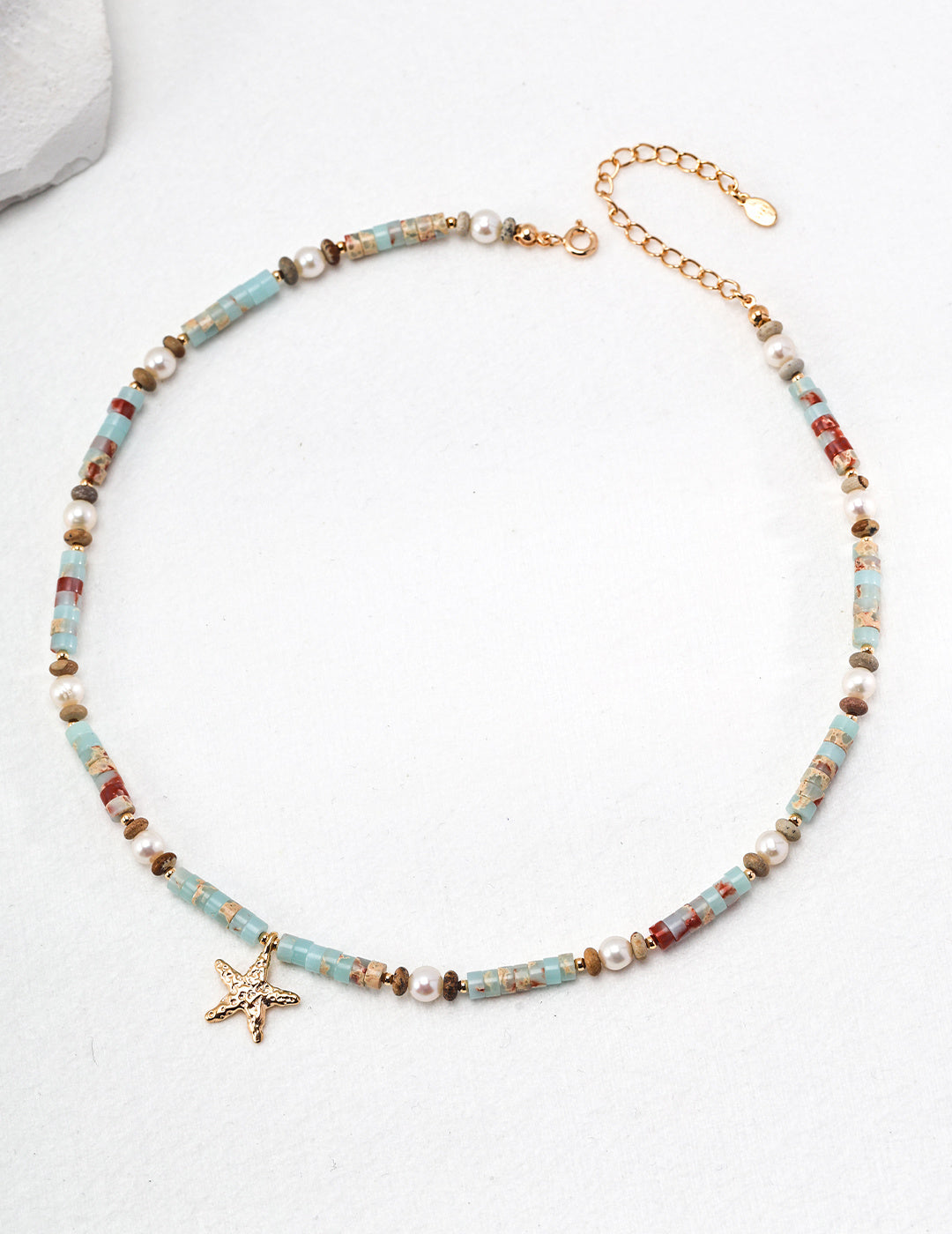 A beautiful necklace featuring a starfish charm and turquoise beads, crafted from agalmatolite for a unique touch.