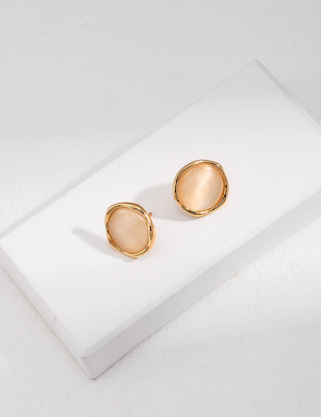 A pair of stunning champagne gold cat's eye earrings on a white surface.