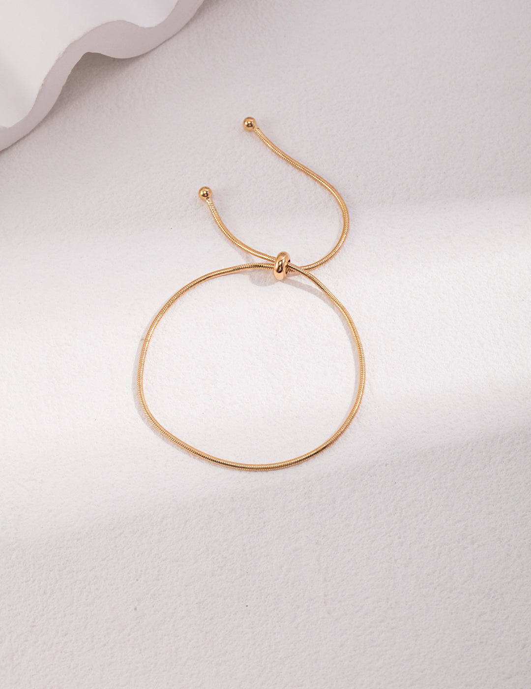 A stylish gold bracelet featuring a sliding ball clasp.