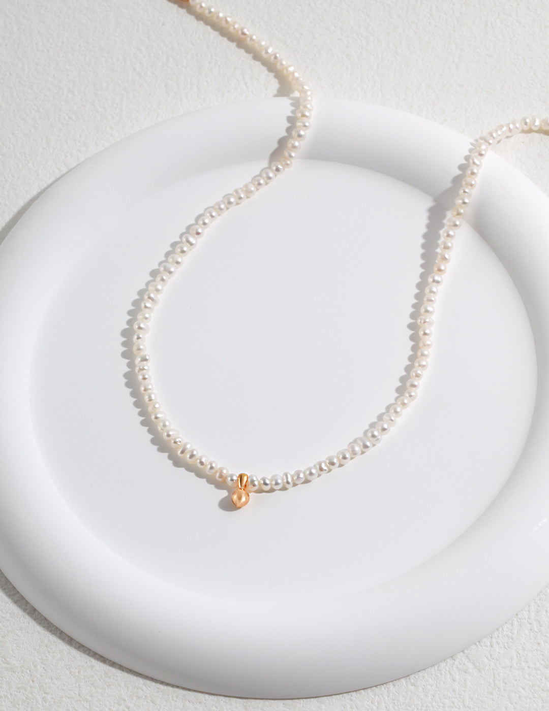 Close-up of elegant pearl necklace with gold plated bead.