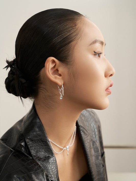 A stylish woman in a black leather jacket and silver jewelry, including icy blue topaz earrings.