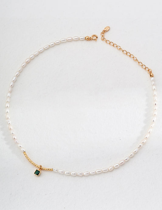 A stunning gold-plated necklace featuring a lustrous pearl and a vibrant green zirconia stone, perfect for any elegant occasion.