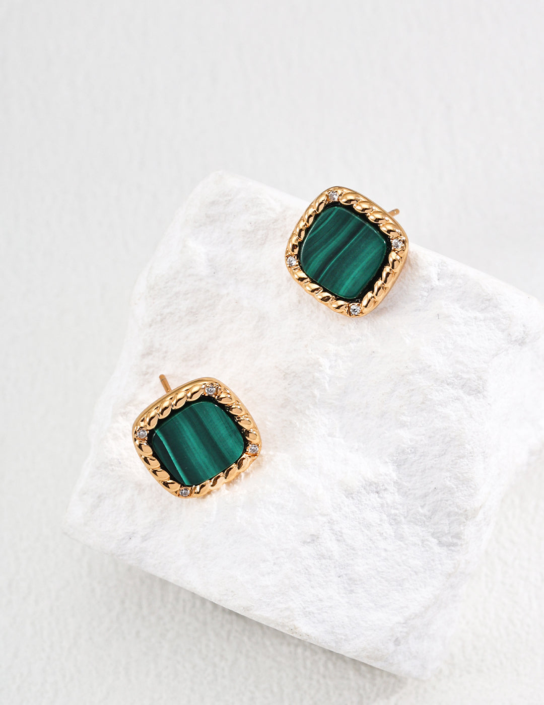 Stunning green malachite earrings adorned with cubic zirconia, showcased on a pristine white stone.