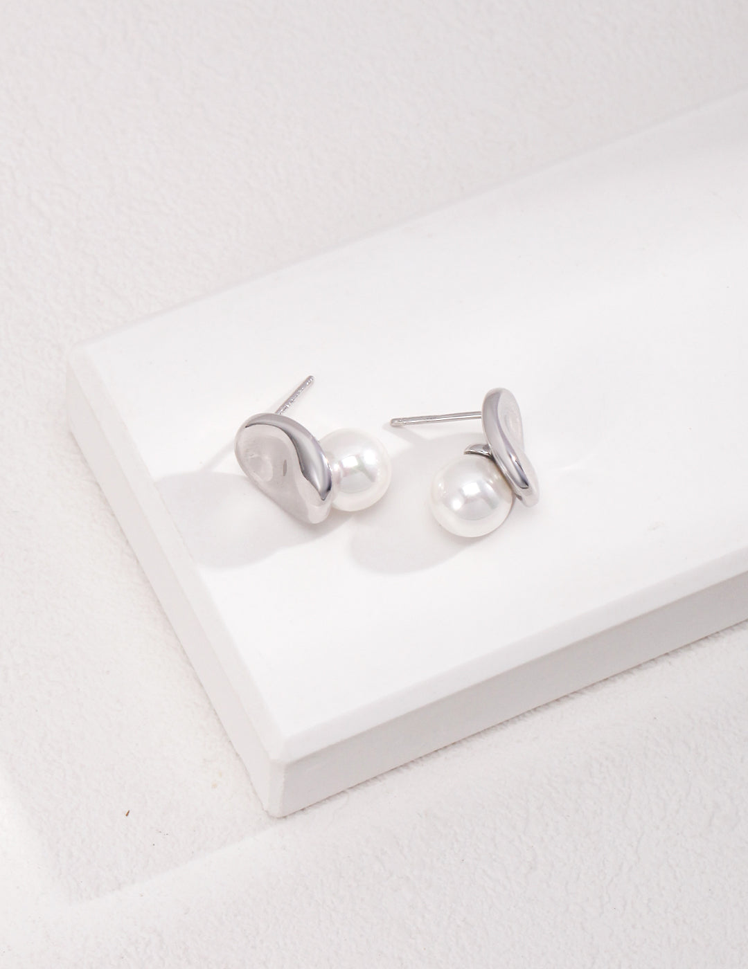 Delicate white shell pearl earrings with silver jellybean studs, displayed on a clean white background.