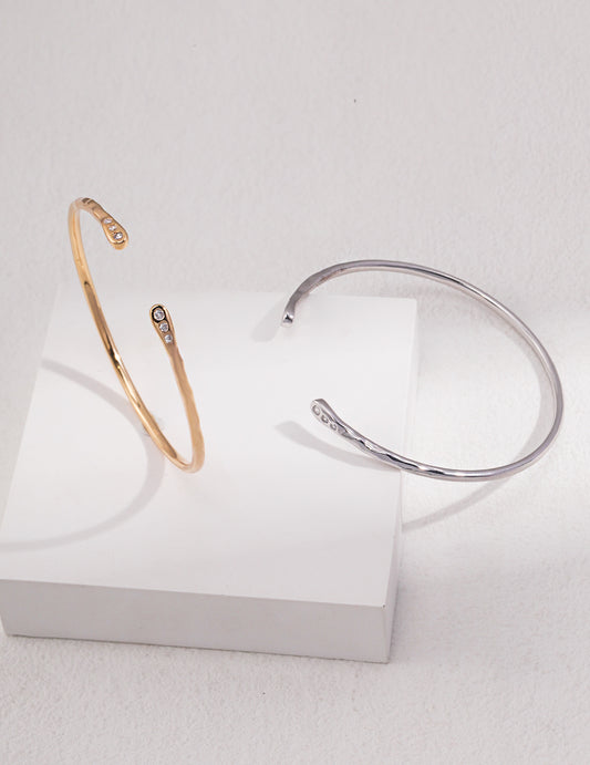 A pair of exquisite silver and gold bangles, beautifully embellished with dainty cubic zirconia, placed on a pure white background.