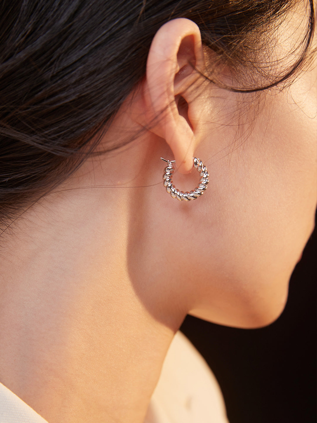 Model showcasing silver twisted hoops.