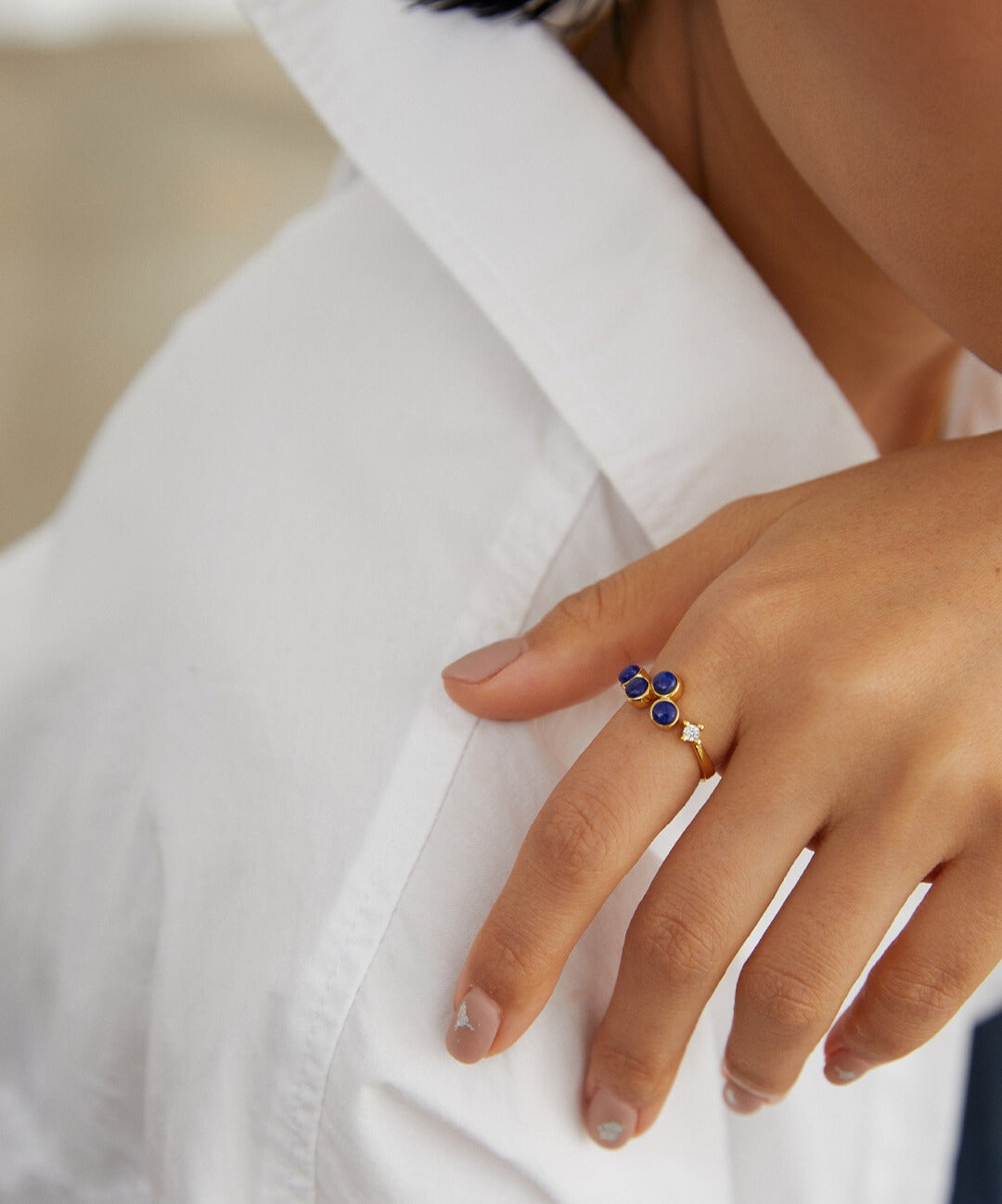 Woman in white shirt with blue ring, wearing gold plated open ring with lapis lazuli and cubic zirconia.