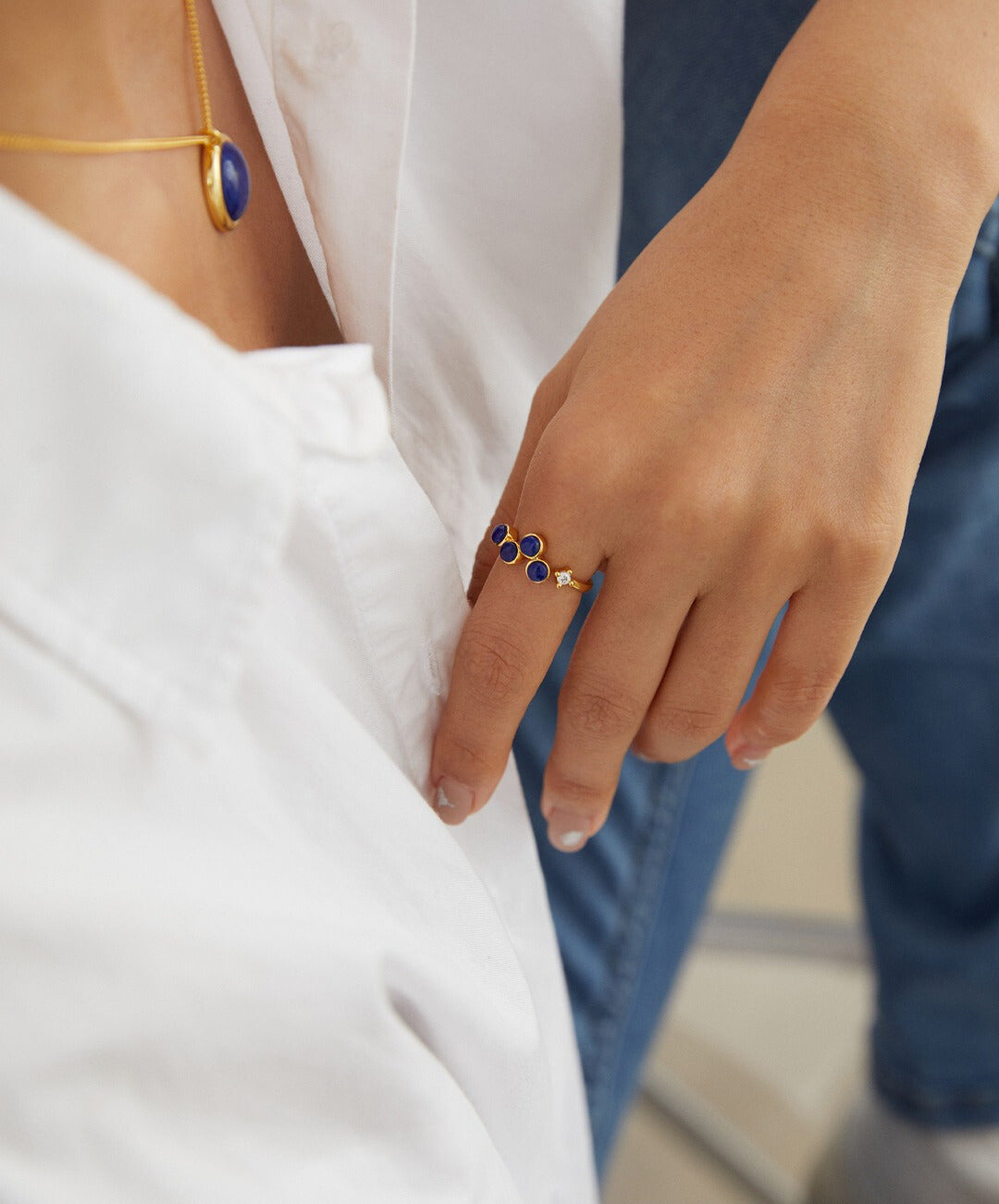 Woman in white shirt with blue and gold jewelry, including gold plated open ring with lapis lazuli and cubic zirconia.