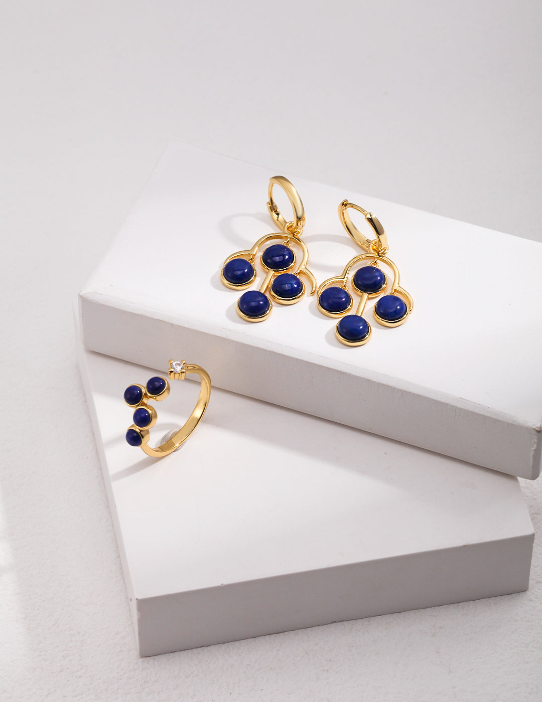 Gold plated open ring with lapis lazuli and cubic zirconia earrings on a white box.