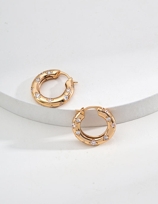 Two elegant gold hoop earrings adorned with sparkling stones on top, showcasing a luxurious and stylish design.