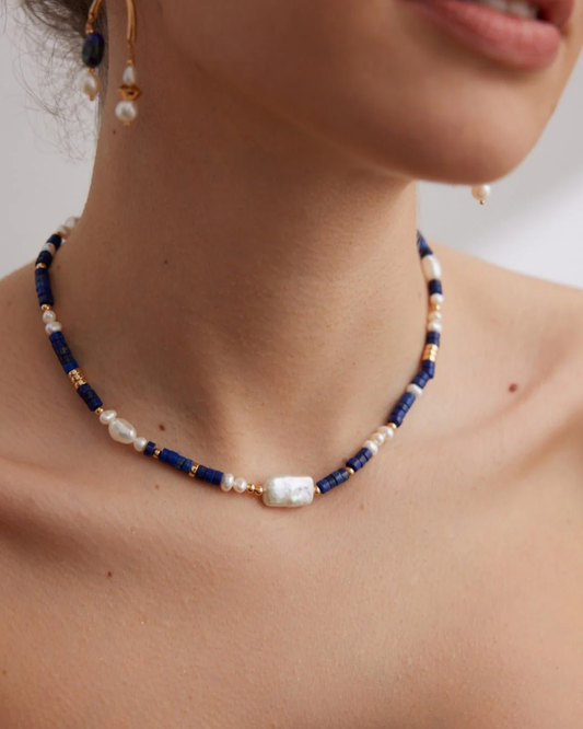 A woman displays a beautiful lapis lazuli necklace in blue and white, enhancing her style with its rich colors.