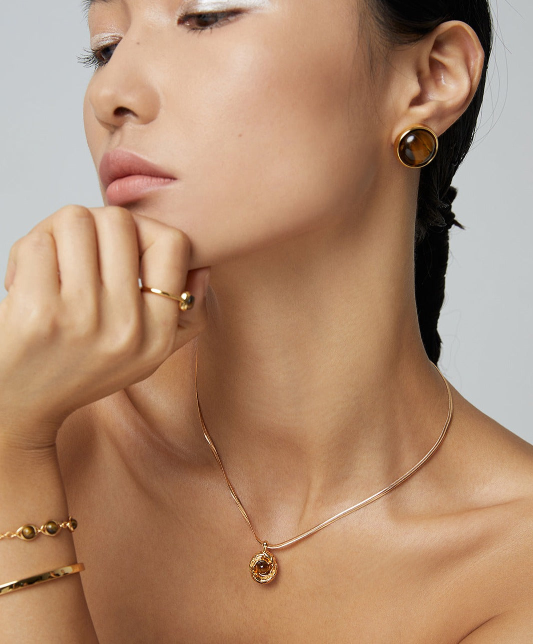 Women accessorized with gold jewelry set, featuring gold tiger's eye necklace.