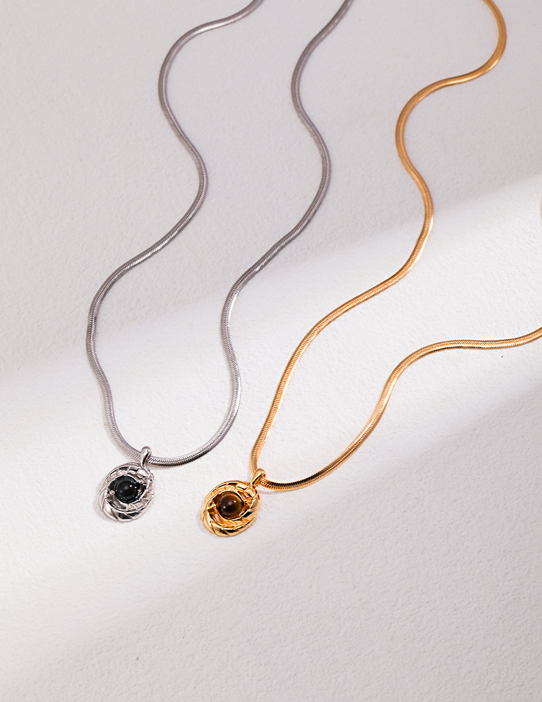 Elegant necklaces with gemstones: one silver with agate, one gold with tiger's eye.