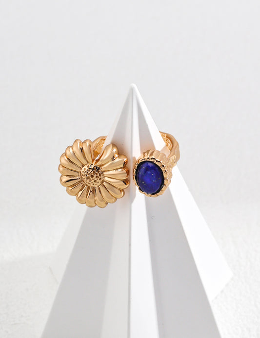 A close-up of a woman's hand grasping a gold ring adorned with a vibrant lapis lazuli, highlighting its exquisite design.