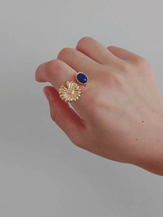 A close-up of a woman's hand grasping a gold ring adorned with a vibrant lapis lazuli, highlighting its exquisite design.