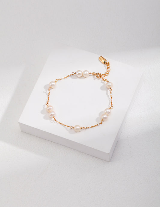 A stunning gold-plated bracelet adorned with lustrous pearls, resting on a pristine white surface.