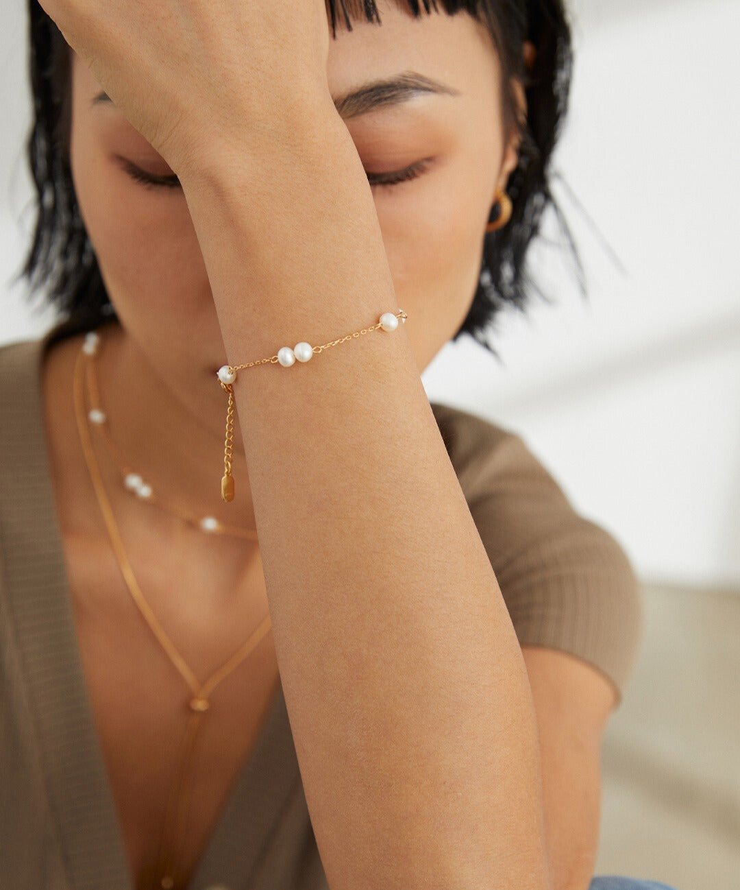 A woman wearing a gold jewelry, featuring a gold plated freshwater pearls bracelet.