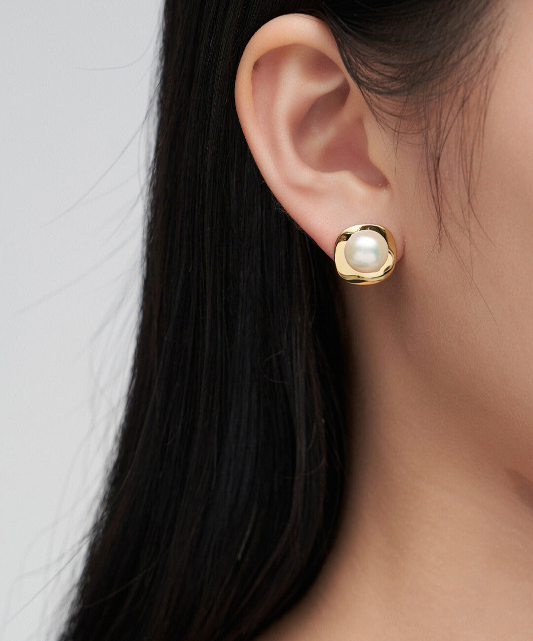 Woman showcasing elegant gold plated pearl earring.