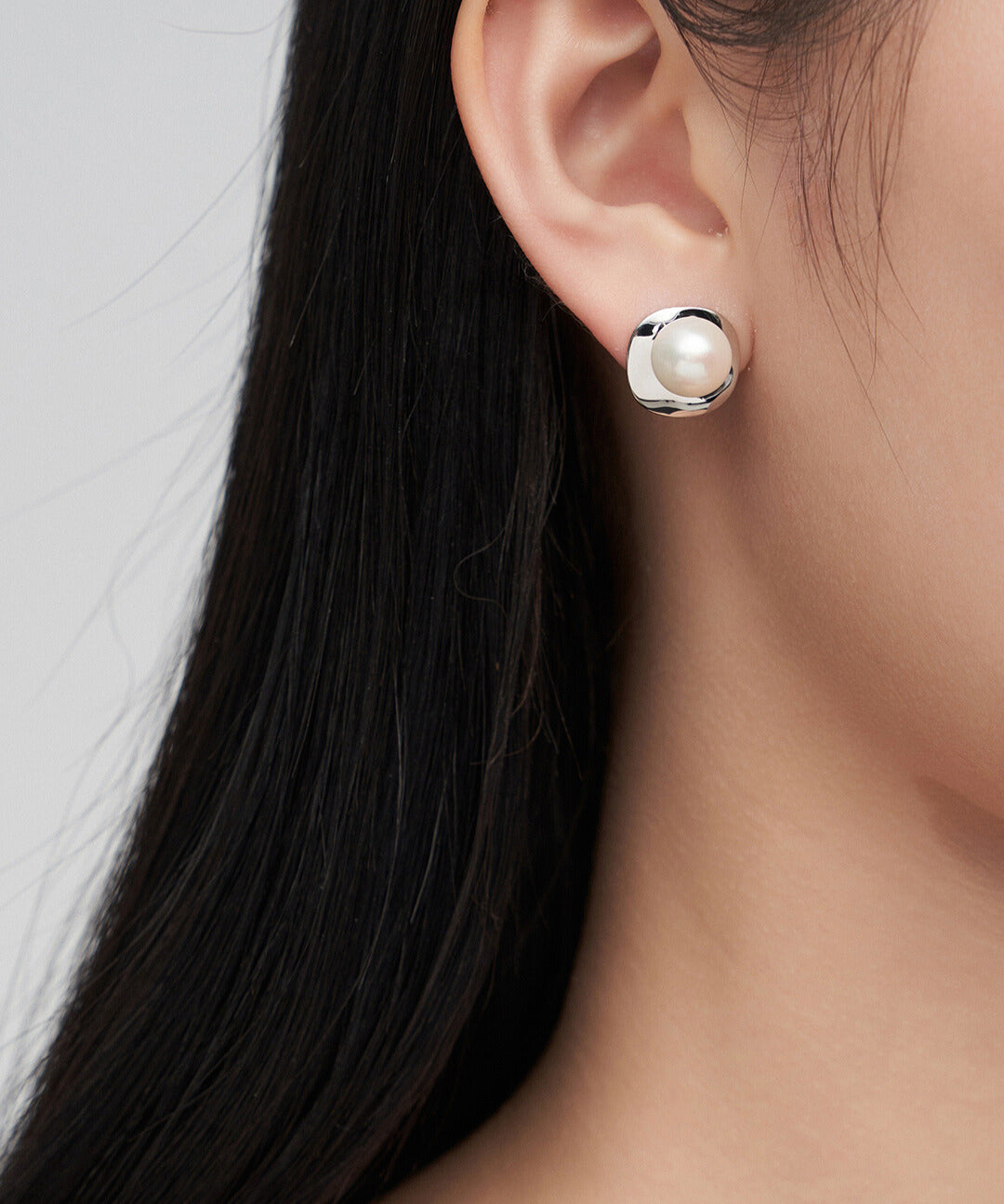 Woman wearing classy silver plated pearl earrings.