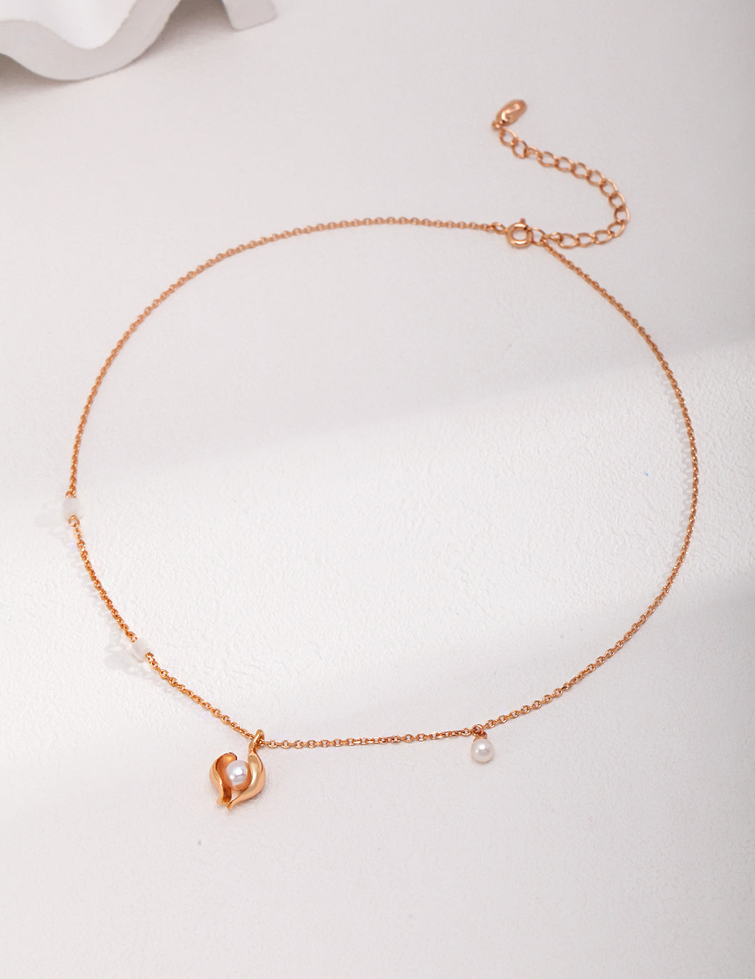 A stunning gold necklace with a heart charm, featuring a nacre pendant with a freshwater pearl in a shell.