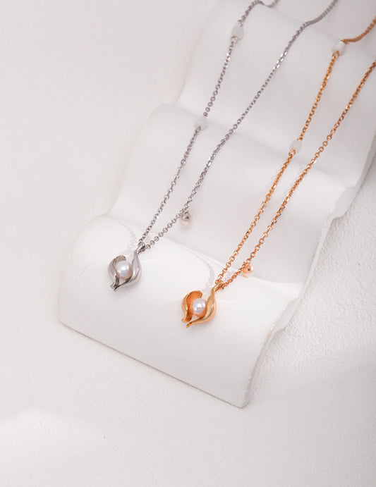 Two elegant necklaces: one with pearls and gold chains, the other featuring a freshwater pearl in a shell pendant.