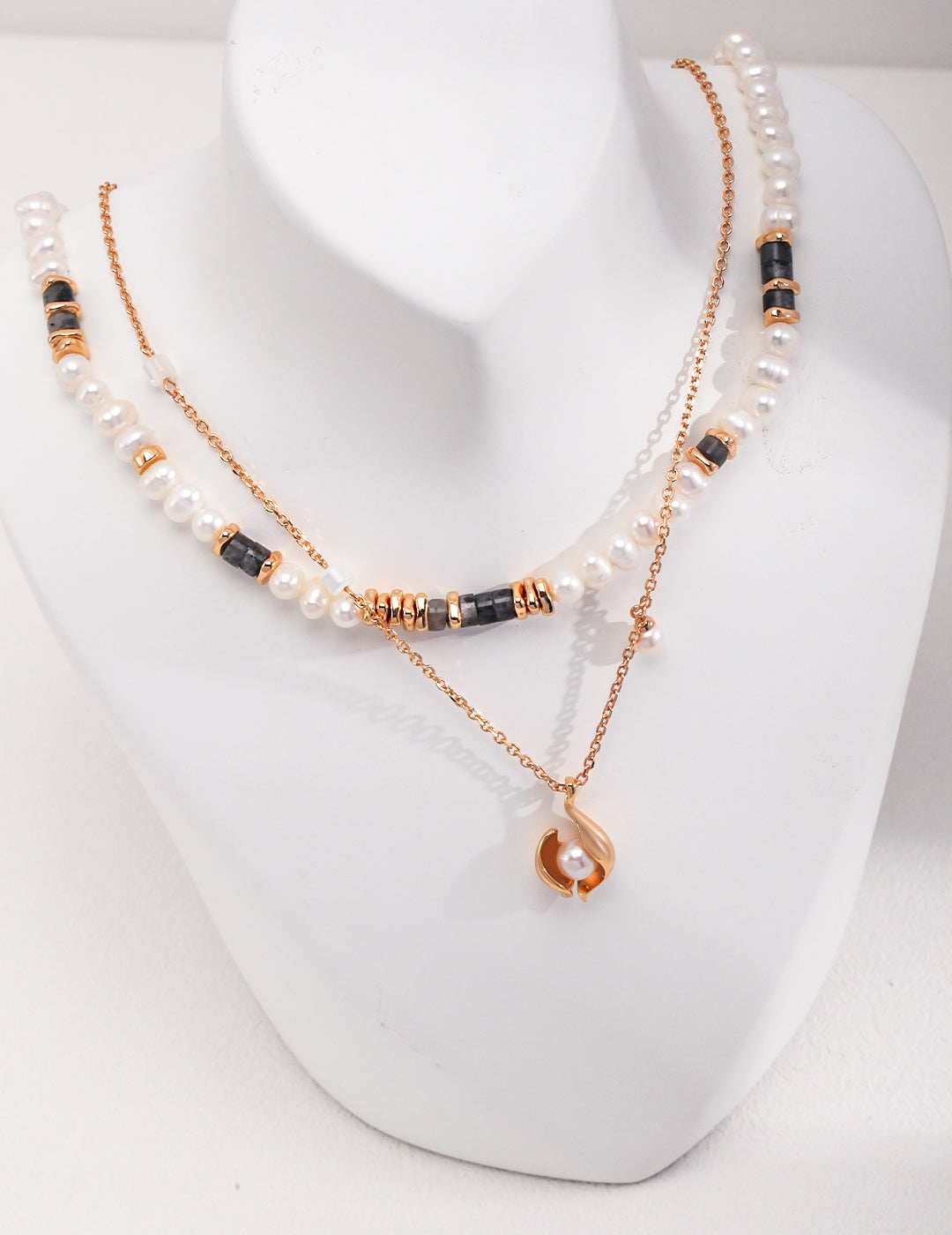 A gold necklace with a pearl pendant and freshwater pearls, featuring a nacre shell pendant.