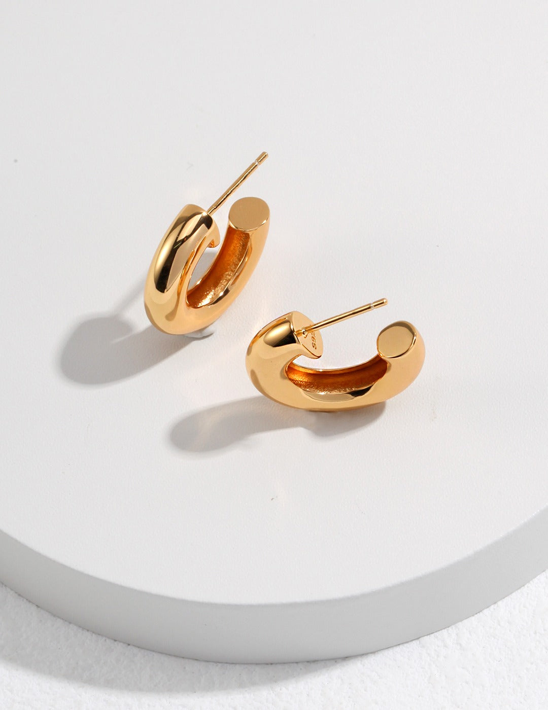 Stylish gold hoop earrings on white background.