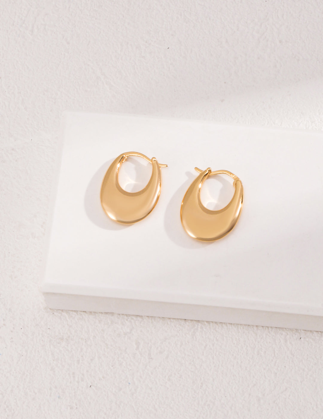 Stylish gold hoops on white background