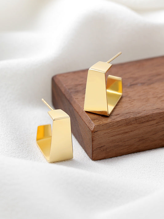 Pair of gold chunky earrings on wood block.