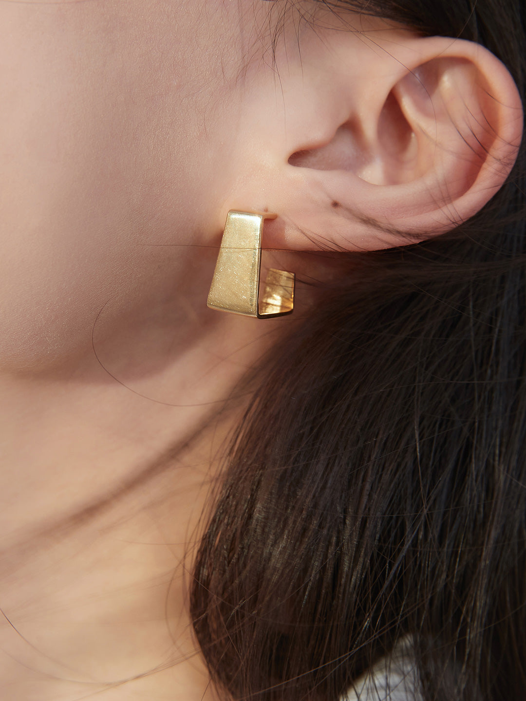 Model with chunky gold square earring.