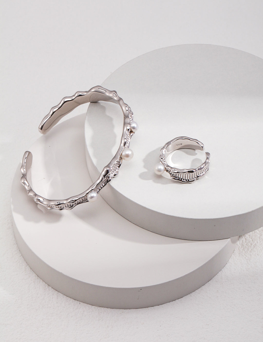 A silver bangle embellished with freshwater pearls and a matching ring.