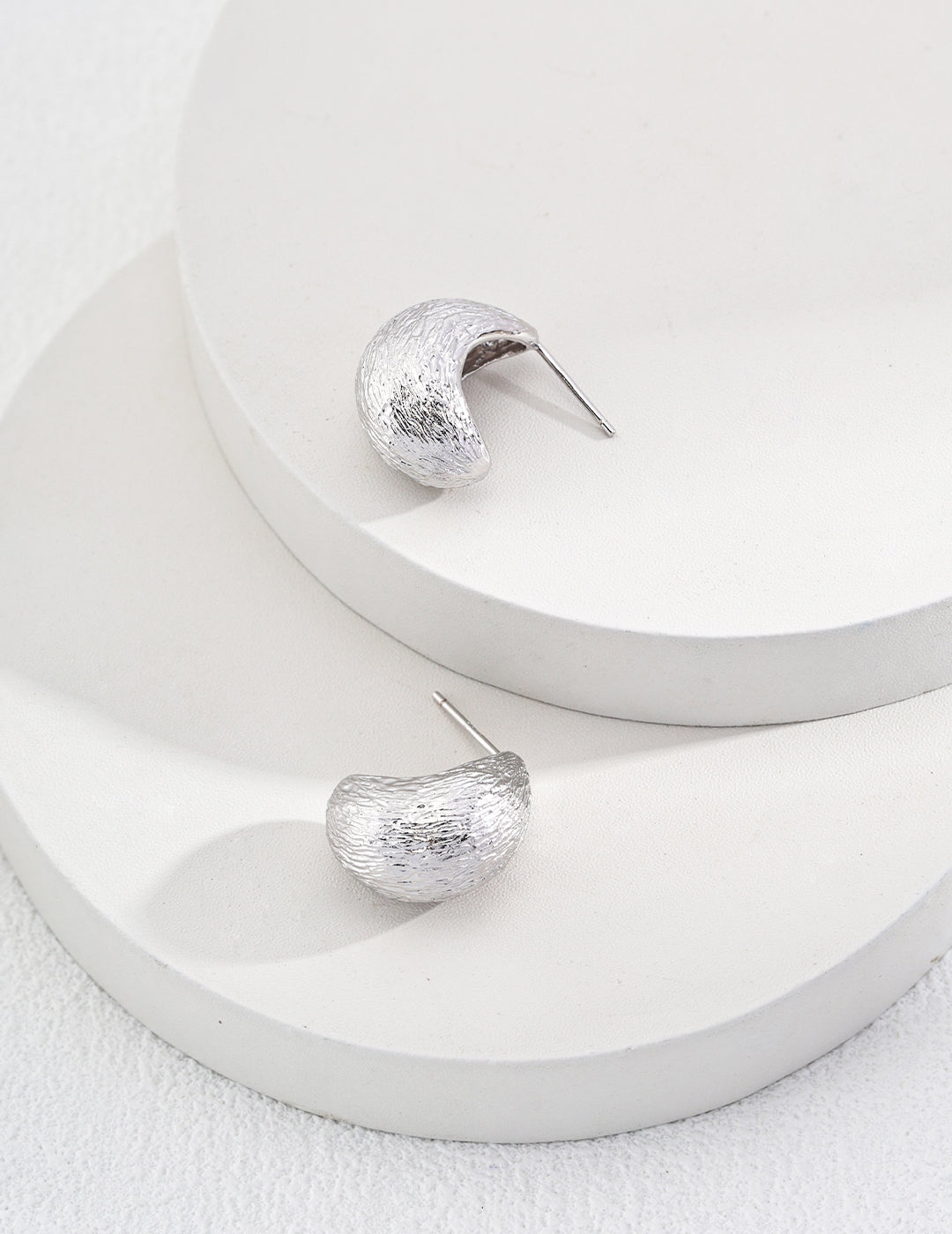 Stylish silver tear drop earrings displayed on plate.