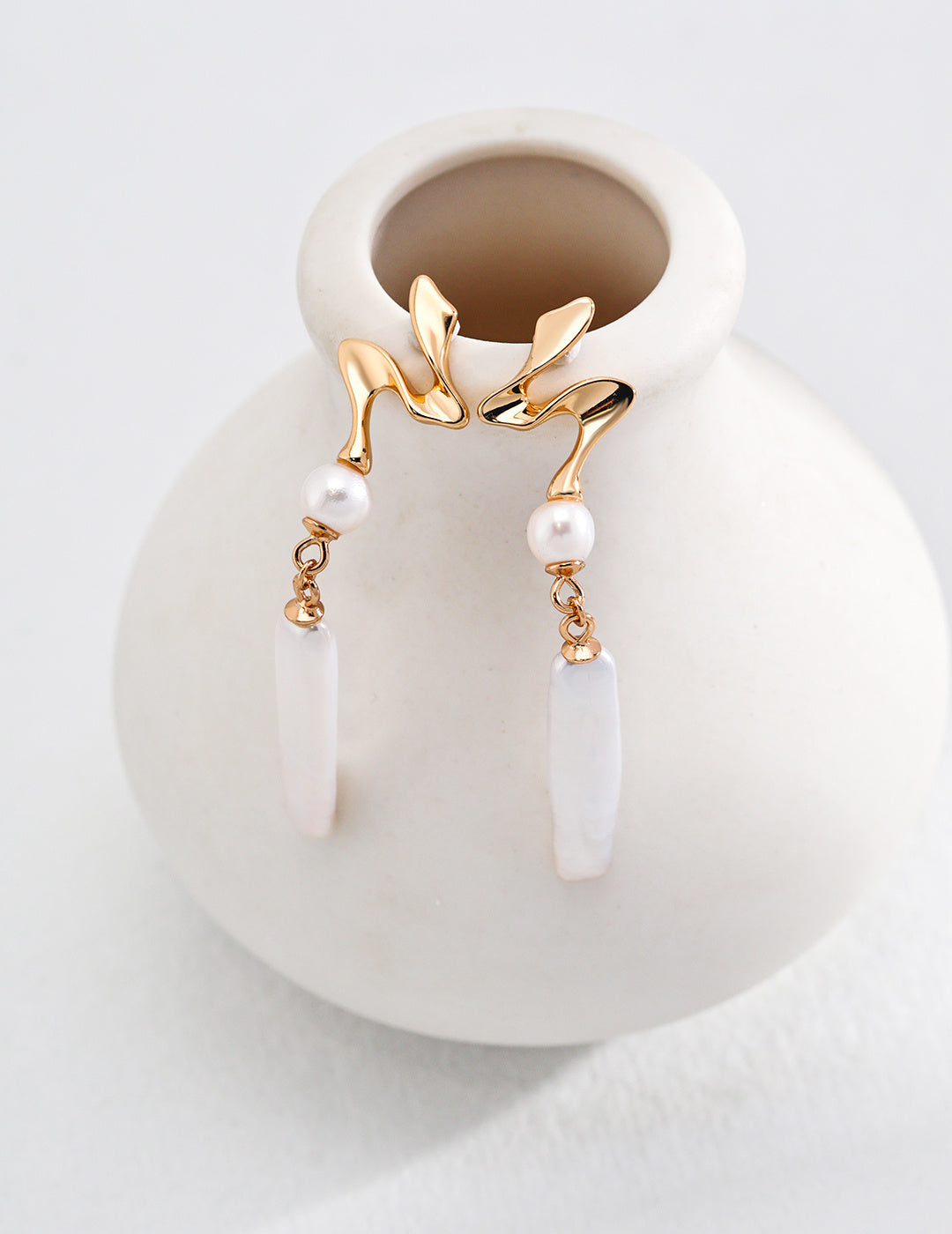 Beautiful gold earrings showcasing a pearl and leaf design, combining nature-inspired elegance with timeless style.