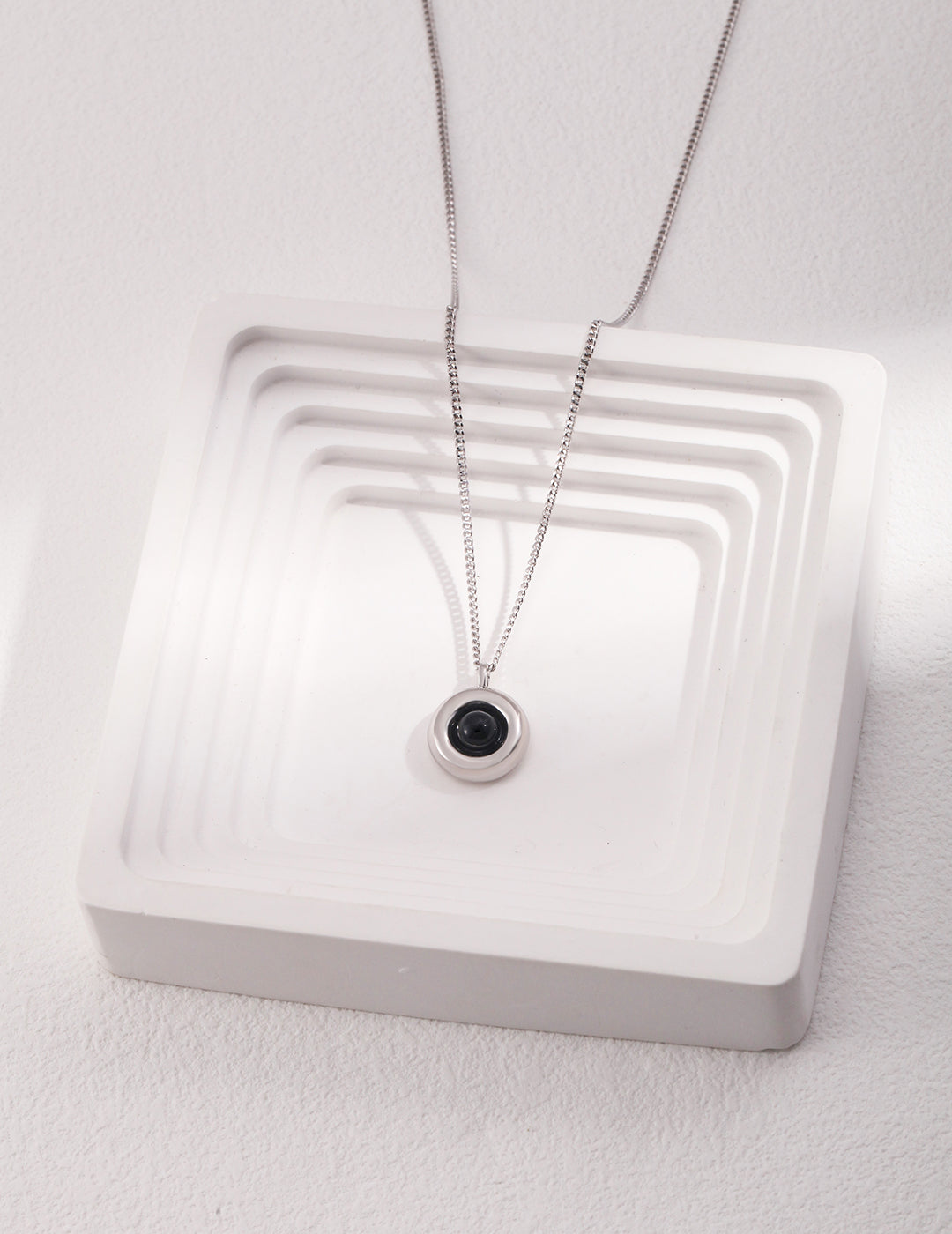 A black agate necklace beautifully arranged on a white tray, emphasizing the elegant interplay of colors and textures.